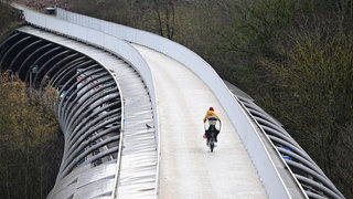 Symbolbild: Eine Radfahrerin fährt über eine Brücke für Radfahrer und Fußgänger in Stuttgart- Vaihingen.