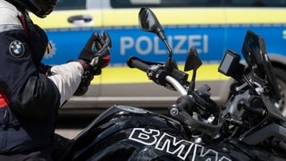 Ein Motorradfahrer sitzt während einer Verkehrskontrolle auf seinem Motorrad (Symbolbild).