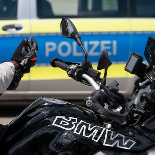 Ein Motorradfahrer sitzt während einer Verkehrskontrolle auf seinem Motorrad (Symbolbild).