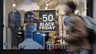 Eine Person geht an einem Plakat im Schaufenster eines Geschäfts vorbei, das auf den "Black Friday"-Tag hinweist (Symbolbild).