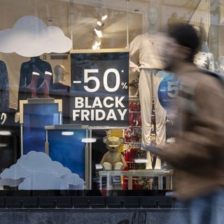 Eine Person geht an einem Plakat im Schaufenster eines Geschäfts vorbei, das auf den "Black Friday"-Tag hinweist (Symbolbild).