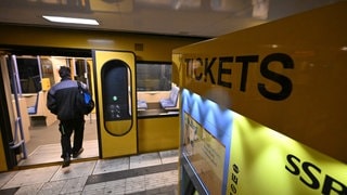 Neben einem Ticketschalter steigt ein Mann in einen Zug der Stuttgarter Stadtbahn. 