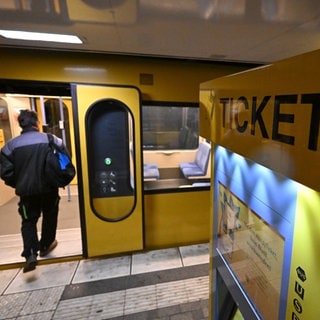 Neben einem Ticketschalter steigt ein Mann in einen Zug der Stuttgarter Stadtbahn. 