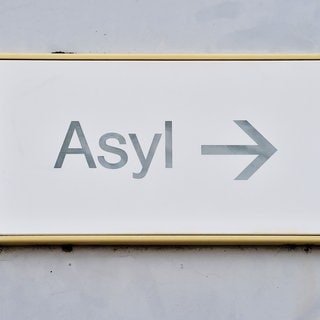 Ein Schild mit der Auschrift "Asyl" hängt bei einer Landeserstaufnahme für Asylbewerber (LEA) an der Wand.