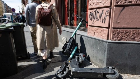 Passanten umgehen falsch abgestellte E-Scooter. (Symbolbild)