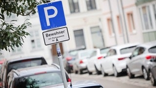 Ein Parkschild steht an einer Straße mit Parkplätzen für Bewohner mit Parkausweis.