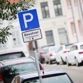 Ein Parkschild steht an einer Straße mit Parkplätzen für Bewohner mit Parkausweis.