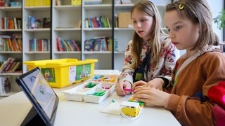 Zwei Mädchen bauen einen von einem Tablet aus steuerbaren Roboter in der Grundschule forum thomanum. 