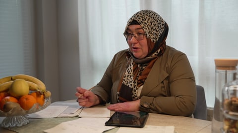 Fatma Şimşek sitzt an ihrem Esstisch. Vor ihr liegen seitenlange Anträge und Schreiben vom Amt. 