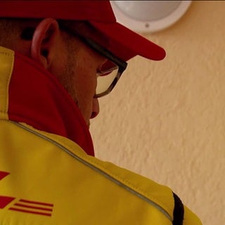 Ein Mitarbeiter von DHL steht vor einer Haustür