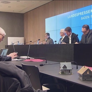 Vier Personen sitzen auf einem Podium und geben eine Pressekonferenz