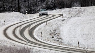 Ein Auto ist bei winterlichen Straßenverhältnissen auf der Schwäbischen Alb unterwegs.