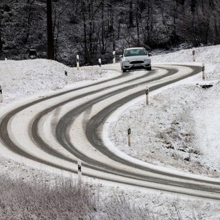 Ein Auto ist bei winterlichen Straßenverhältnissen auf der Schwäbischen Alb unterwegs.