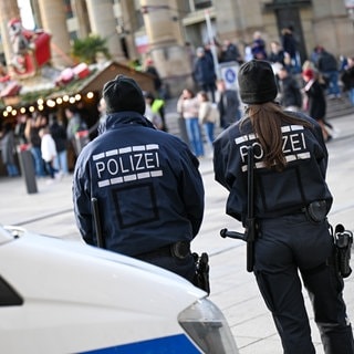 Zwei Polizisten stehen am Mittag auf einer Zufahrtsstraße zum Weihnachtsmarkt in Stuttgart. Nach einer Attacke auf einen Weihnachtsmarkt in Magdeburg wurden die Sicherheitsvorkehrungen verschärft.