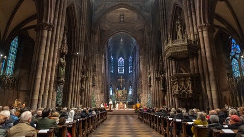 Menschen hören der Weihnachtspredigt des Freiburger Erzbischofs Stephan Burger im Münster zu.