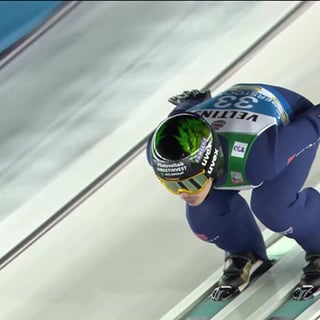 ein Skispringer nimmt auf einer Sprungschanze mächtig Schwung