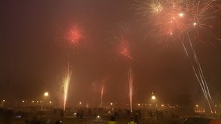 Menschen lassen in der Stuttgarter Innenstadt Feuerwerksraketen in die Luft steigen.