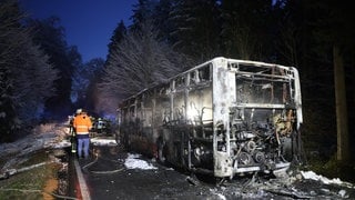 Feuerwehrleute stehen neben einem augebrannten Bus. Ein Linienbus ist bei Mittelbiberach (Kreis Biberach) in Brand geraten. Wie die Polizei mitteilte, waren beim Ausbruch des Feuers am Freitagmorgen zwei Fahrgäste sowie der Fahrer im Bus. Alle Insassen hätten sich unverletzt in Sicherheit gebracht, bevor die Flammen auf das gesamte Fahrzeug übergriffen.