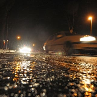 (Symbolbild) Ein Auto fährt auf einer eisglatten Straße.