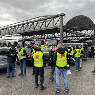 Streikende stehen in Ludwigsburg vor einem Omnibus-Terminal.