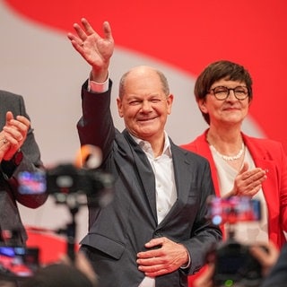 Bundeskanzler Olaf Scholz winkt neben SPD-Parteichef Lars Klingbeil und Parteichefin Saskia Esken beim außerordentlichen SPD-Bundesparteitag zur Kür des SPD-Kanzlerkandidaten den Delegierten zu.