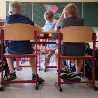 Schülerinnen und Schüler sitzen in einer Grundschule in einem Klassenraum.