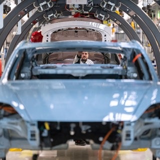 Ein Mitarbeiter der Porsche AG montiert in einer Produktionshalle des Porsche-Stammwerks einen Porsche Taycan. Tausende Stellen in der deutschen Autoindustrie wurden 2024 abgebaut. Welche Herausforderungen müssen Hersteller angehen, um aus der Krise zu kommen?