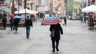 Ein Mann geht bei Regen mit einem Regenschirm durch die Innenstadt von Rottweil