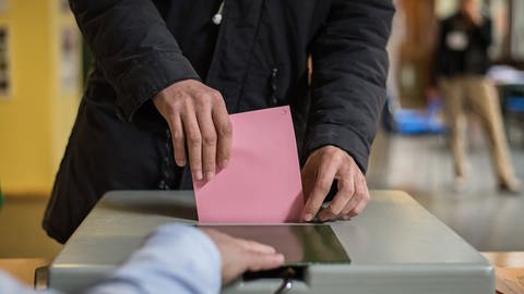 Symbolbild für BW-Trend "... wenn am kommenden Sonntag Landtagswahl in Baden-Württemberg wäre.", Wähler wirft Stimmzettel in Wahlurne