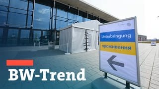 Ein Hinweisschild zeigt den Weg für Flüchtlinge aus der Ukraine in eine Messehalle an der Messe Stuttgart. Teaserbild mit Schriftzug "BW Trend" als Symbolbild für die landespolitische Umfrage. 