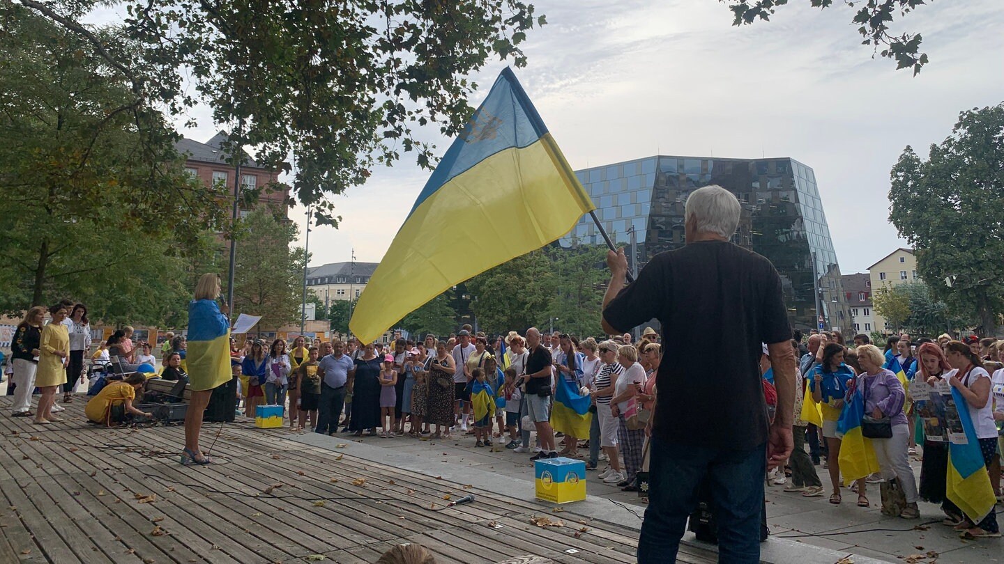 Eine Kundgebung man sieht eine Flagge der Ukraine.