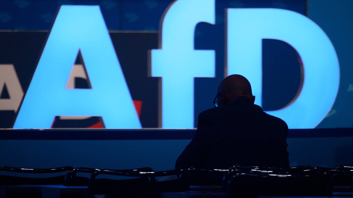 Ein Delegierter der AfD vor dem Logo der Partei.