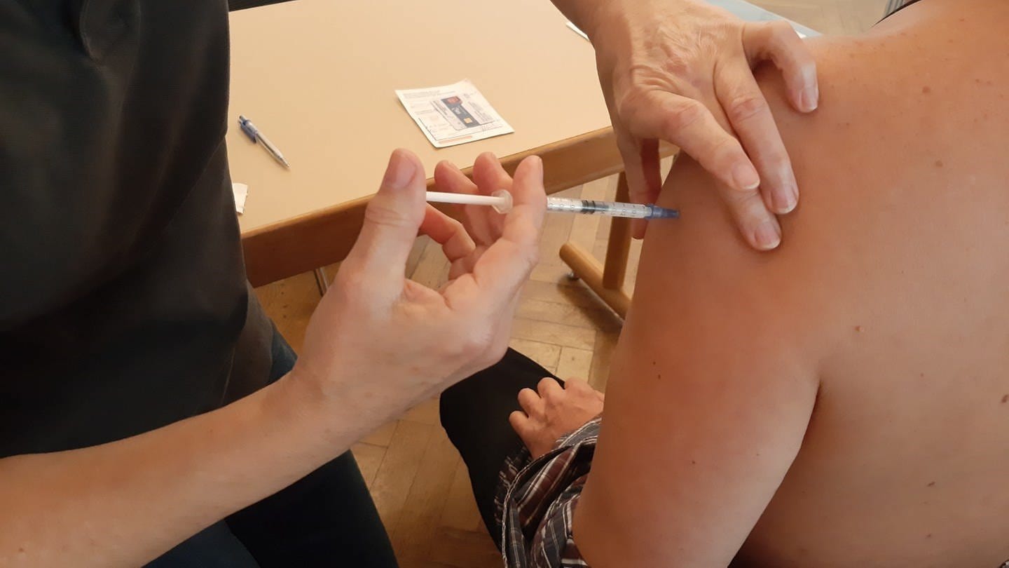 Ein Mensch bekommt eine Booster-Impfung in den Arm gespritzt