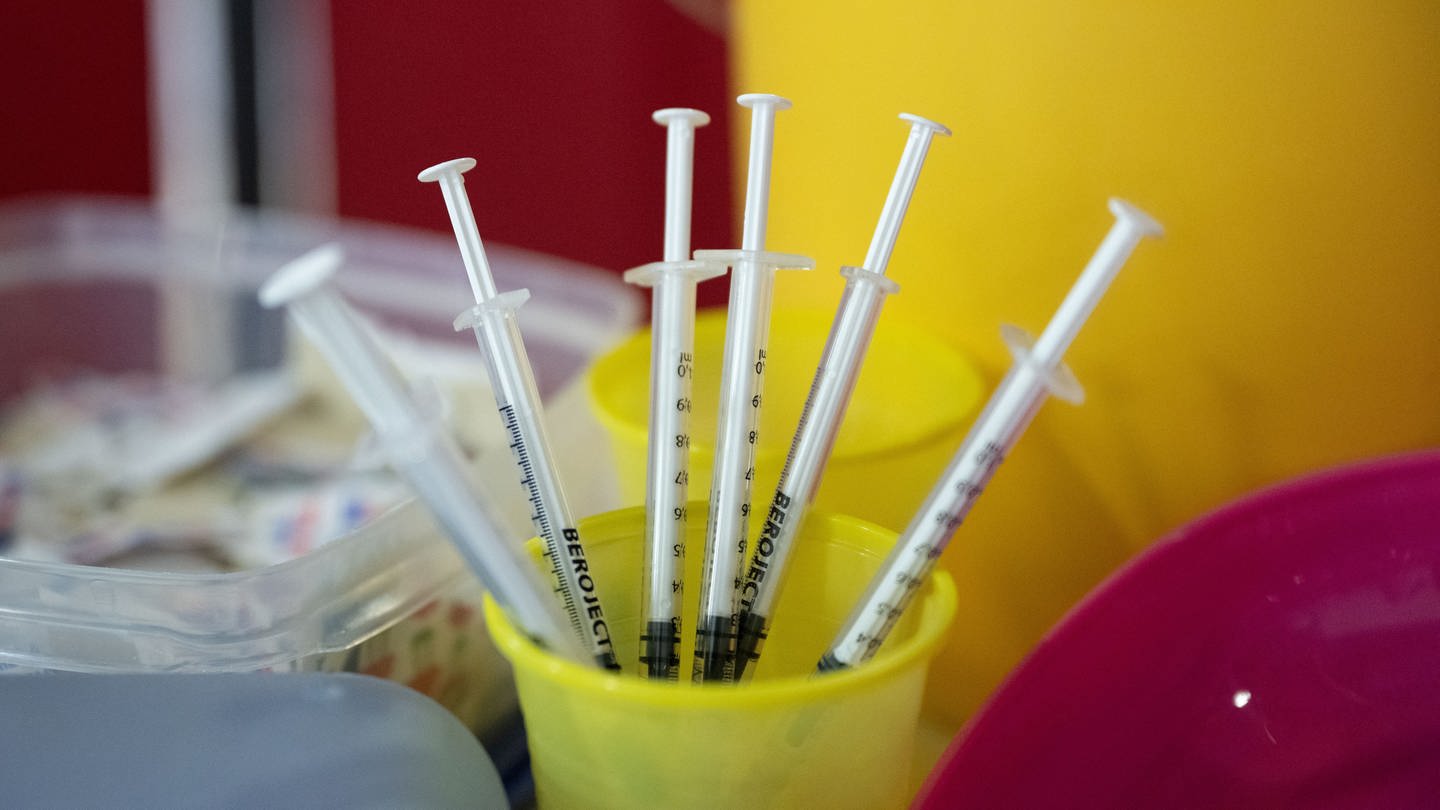 Spritzen für eine Impfung stehen an einem Impfstützpunkt mit dem Titel 