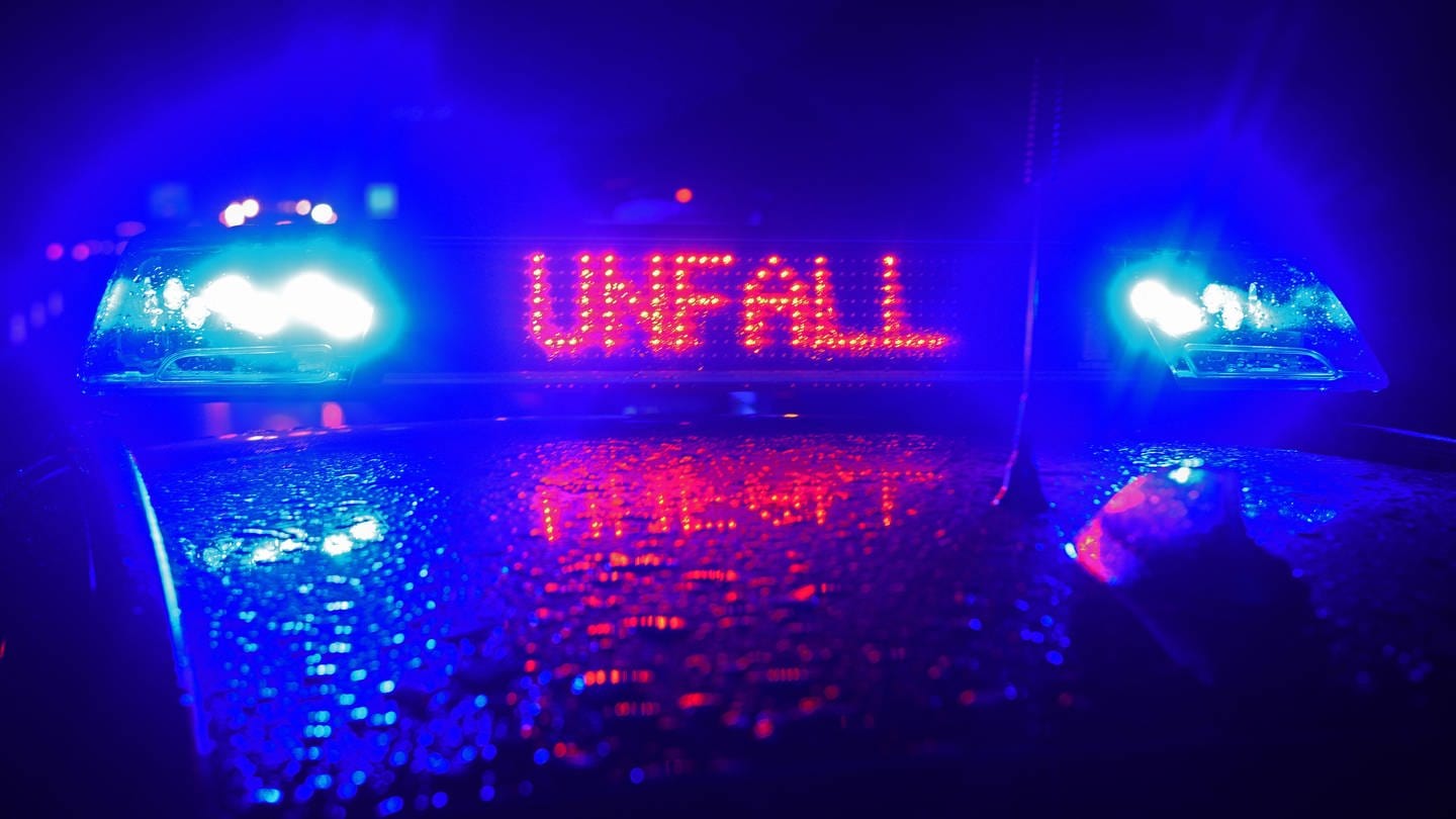 Dach eines Polizeifahrzeugs bei Dunkelheit, zwei blaue Lichter umrahmen rote Schrift 