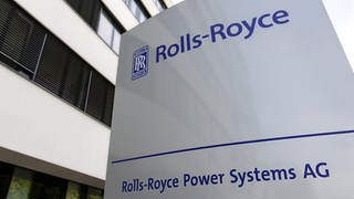 Vor einem Gebäude steht ein Firmenschild mit der Aufschrift "Rolls-Royce Power Systems AG"