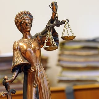 Justizia-Figur vor Aktenstapeln