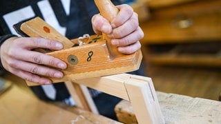 Schreiner hobelt einen Holzrahmen glatt