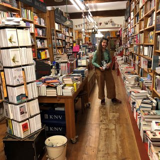 Anna Rahm steht in ihrer Bücherei vor Regalen voller Bücher.