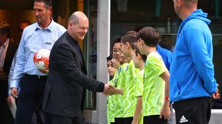 Bundeskanzler Olaf Scholz begrüßt bei einem Besuch des Sportvereins VfB Friedrichshafen junge Fußballspieler