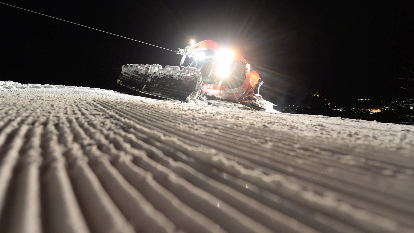 Eine Pistenraupe fährt über eine Skipiste.