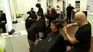 Menschen bekommen beim Frisör die Haare gewaschen
