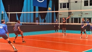 Volleyballer spielen auf Volleyball-Feld in Flugzeughangar-Halle in Friedrichshafen