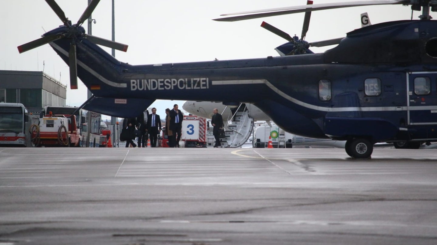 Kanzler Scholz (rechts) steht neben Treppe von Regierungsflugzeug am Flughafen Friedrichshafen