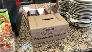 Spendenbox neben einer Kasse im Döner-Imbiss