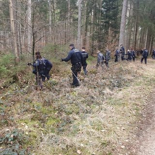 Polizistinnen und Polizisten durchkämmen einen Wald bei Heudorf.