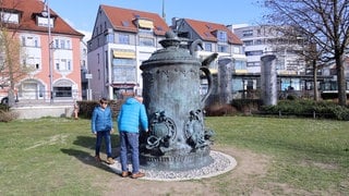 Eine große Skulptur eines Bierkruges mit Deckel steht auf einer Wiese an der Seepromenade in Friedrichshafen.