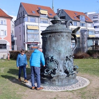 Eine große Skulptur eines Bierkruges mit Deckel steht auf einer Wiese an der Seepromenade in Friedrichshafen.