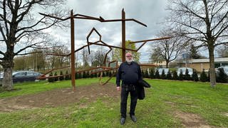 Der Künstler Robert Schad steht vor seiner Skulptur "der Schrei", einem abstrakten Kunstwerk aus rostbraunem Stahl