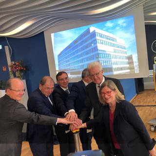 Ministerpräsident Winfried Kretschmann drückt mit anderen Verantwortlichen auf einen Startknopf in Biberach